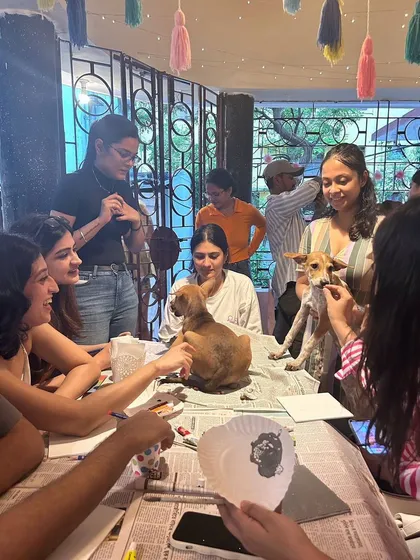 A lively group of participants enjoying the art session, with puppies being cuddled and played with all around.