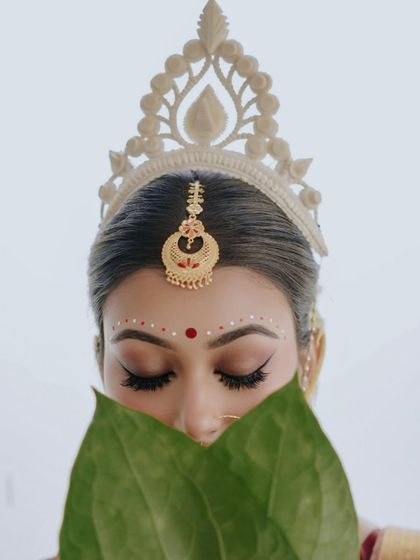 A close-up on the eyes. The 'topor' and the betel leaves frame her face, drawing all attention to her expressive, kohl-lined eyes.