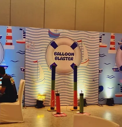 Game stalls at a sailor party, including themed areas for tattoos and balloon blasters, all set against a wave-patterned backdrop.