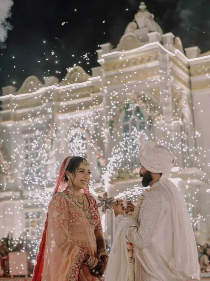 We love capturing the grand scale of your celebration. This stunning varmala moment, set against a beautifully lit palace facade with a brilliant display of cold pyro fireworks, highlights our expertise in filming large, destination weddings and turning them into spectacular cinematic events.