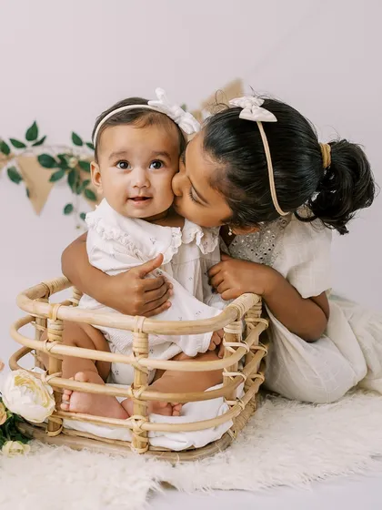 A sweet moment between a big sister and her baby sister during a six-month milestone shoot. Sibling love is always beautiful to capture.