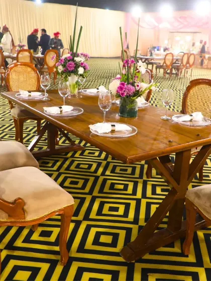 An elegant outdoor dining setup with wooden tables and classic chairs. We excel in curating memorable royal moments, ensuring every detail of your event is perfect.
