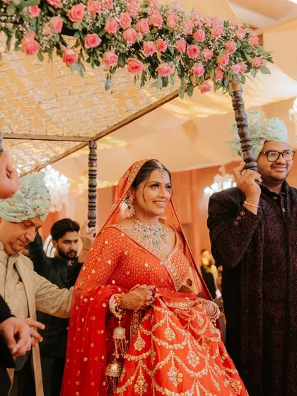 A beautiful bride making her way to the mandap under a floral canopy. The warm lighting and her radiant smile capture the anticipation and happiness of this special walk.