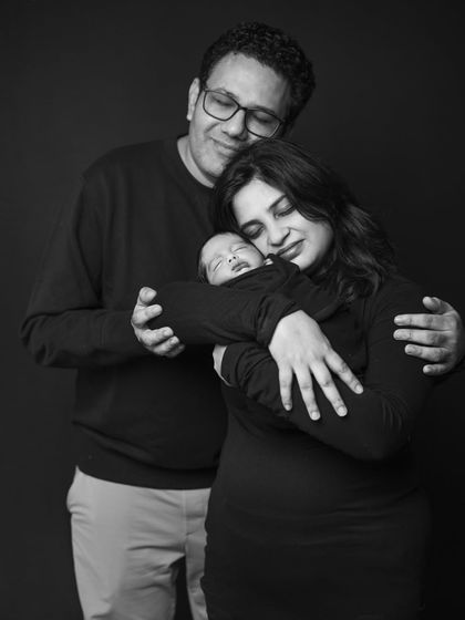An intimate black and white photo of a new family sharing a hug. This pose creates a feeling of closeness and unity, beautifully capturing the love that surrounds the baby.
