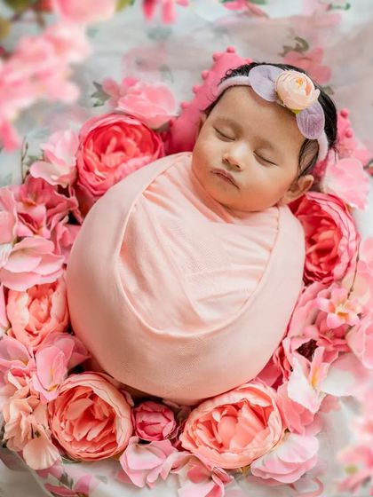 Surrounded by a bed of pink flowers, this baby girl looks like a sleeping angel. Floral themes are a beautiful way to add color and softness to your newborn's portraits.