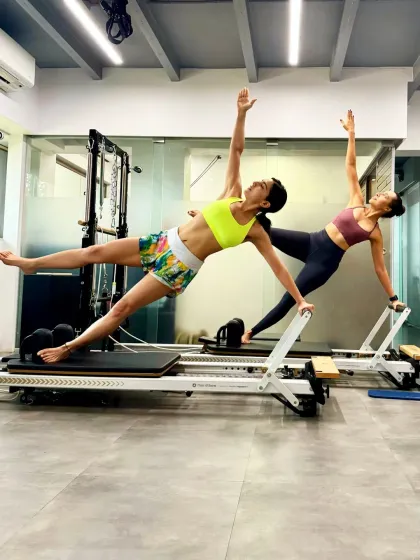 Sara Ali Khan and Namrata Purohit in a synchronized star plank on the reformers. This advanced move requires immense core control, shoulder stability, and balance, showcasing the peak fitness levels achieved through dedicated Pilates practice.