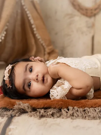 A 5-month-old baby girl in a boho-themed setup, looking curious and sweet.