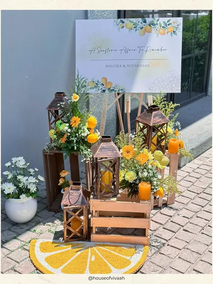 A welcome vignette for the sunflower Haldi, with rustic lanterns, wooden crates, and a lemon-slice rug, creating a cheerful and inviting entrance.