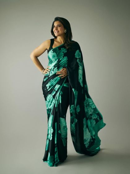 Kajol in a striking black and green floral saree, a bold and modern choice for promotional events.