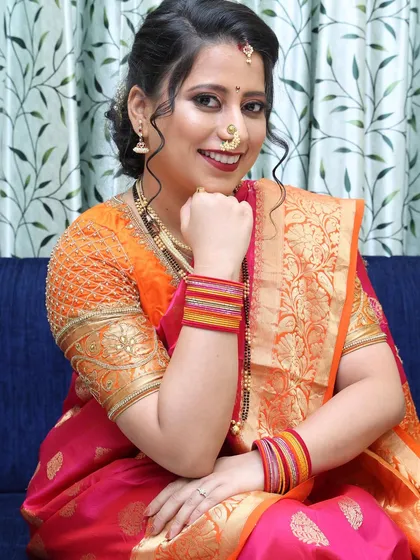 A classic Marathi bridal look with a twist. The makeup is glamorous yet refined, with a beautiful hairstyle that complements her embroidered blouse.