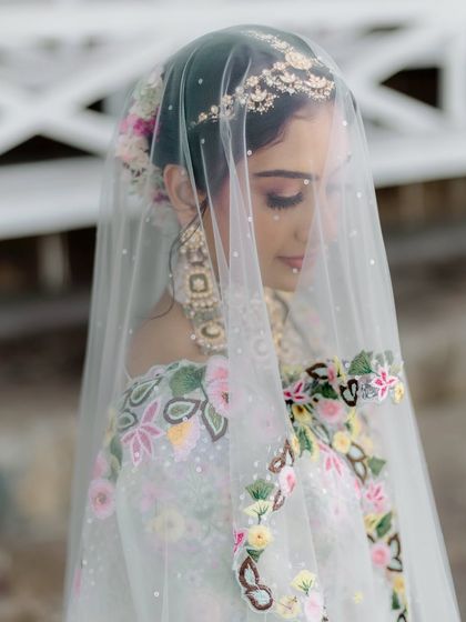 A classic shot through the veil. Bhoomi's soft eye makeup and glowing skin are visible, creating an ethereal and romantic bridal portrait.