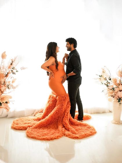 A candid moment of connection between the couple, framed by the beautiful texture of a vibrant orange gown.
