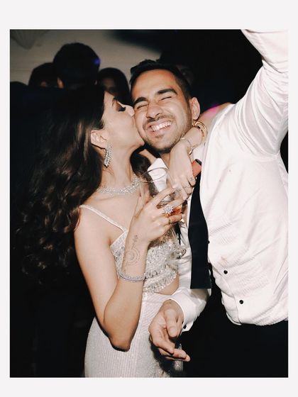A sweet kiss on the cheek amidst the party. This candid shot shows that even in a crowd, a couple can create their own intimate world.