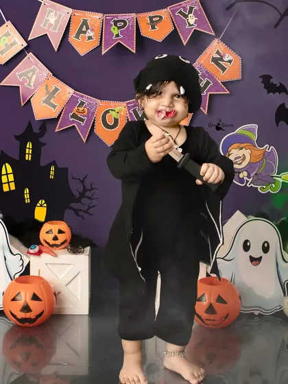 This little vampire is ready for some Halloween fun. The messy hair and playful pose make for a memorable and spooky-cute portrait.