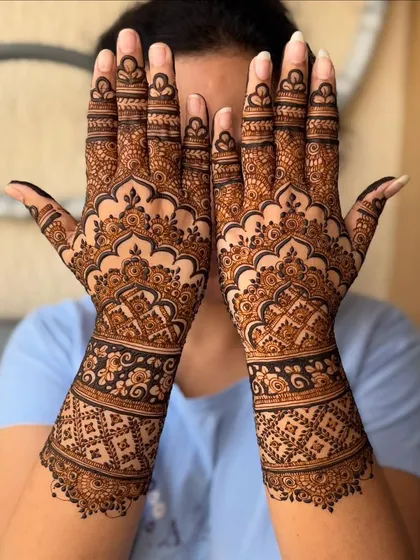 A lovely engagement mehendi with geometric grid work on the wrists and flowing patterns on the palms.
