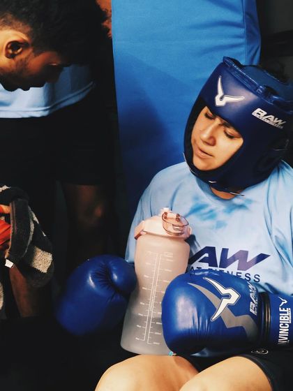 A female fighter rests between rounds, showing the exhaustion and determination of competition.
