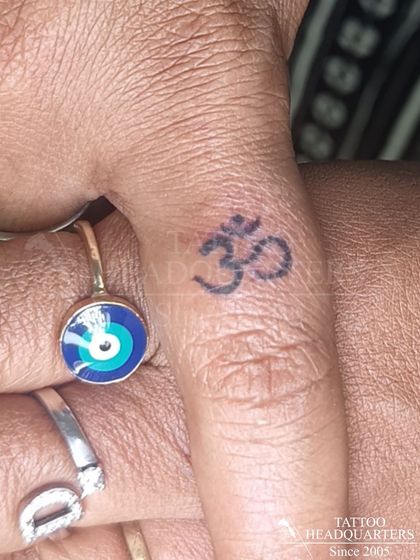 A small, subtle Om tattoo on the finger, a constant and personal reminder of the universal sound and spiritual connection.