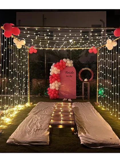 For this garden bridal shower, we constructed an enchanting walkway with a canopy of fairy lights. The setup includes low floor seating and a custom "Bride to be" panel with a balloon arch, creating a magical entrance and party space.
