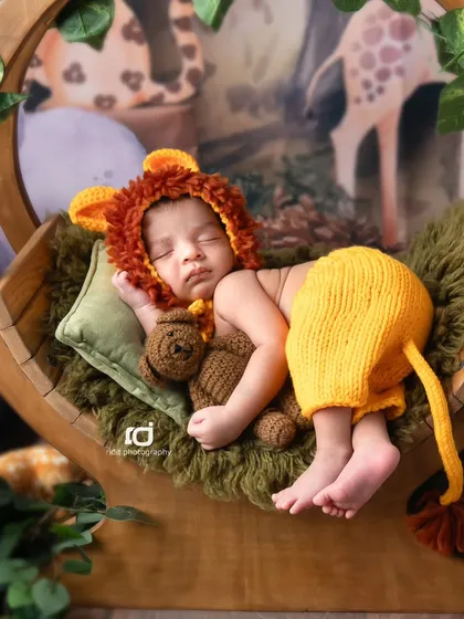Cuddling a teddy bear, our little Simba is sleeping soundly in his jungle-themed swing.