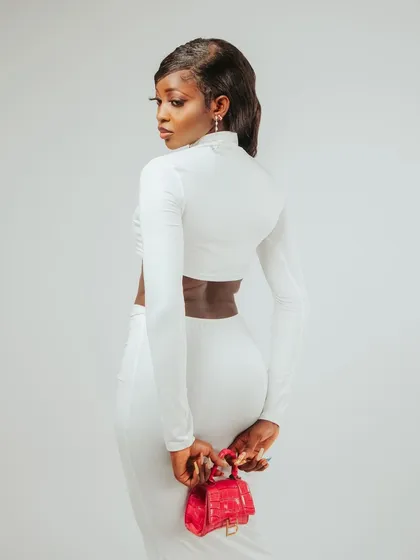 A back-profile shot that highlights the cut of the top and the pop of color from the red handbag.
