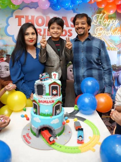 A happy family portrait from Damian's 7th birthday party, with the custom Thomas cake ready for the celebration.