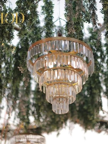 A close-up of a beautiful tiered crystal chandelier, a key artistic detail that adds a touch of luxury and sparkle to the wedding decor.