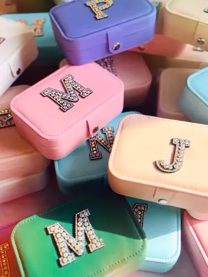A pile of our super popular personalised jewellery boxes in a rainbow of pastel colors. Each box is customised with a sparkling rhinestone initial, ready to be gifted.