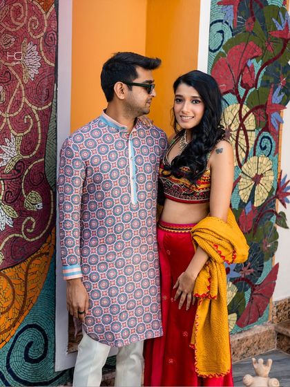 A beautiful couple moment, where his printed kurta complements the vibrant colors of the decor and her outfit, creating a harmonious festive picture.
