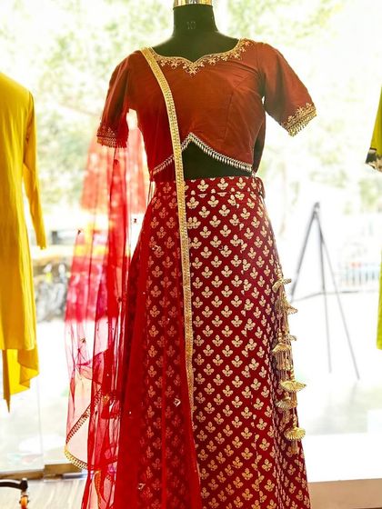 Your dream wedding lehenga, designed just for you. This red brocade lehenga with a matching blouse and net dupatta is a perfect example of classic bridal elegance.