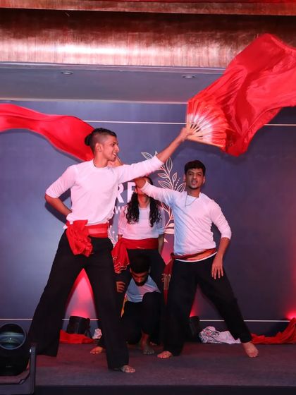 Our dancers use props like these vibrant red fans to add color and movement to the performance. This shot captures the energy and artistry of our Indian fusion choreography during a corporate showcase.
