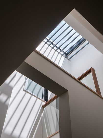 Light is the only ornament this home needs. A linear skylight brings daylight into the vertical core of the home, creating a rhythmic play of shadows across the minimalist corridor.