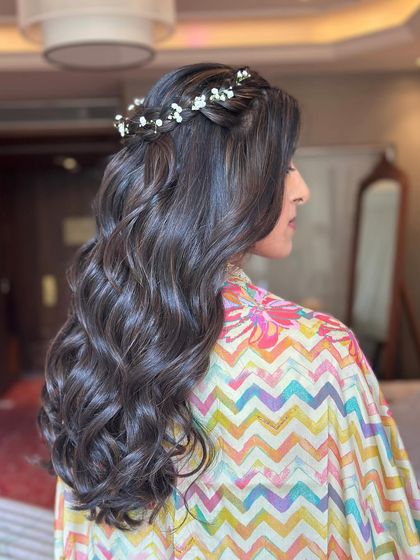 A half-up style with a crown braid and soft waves, adorned with delicate baby's breath. This look is the definition of romantic and ethereal.