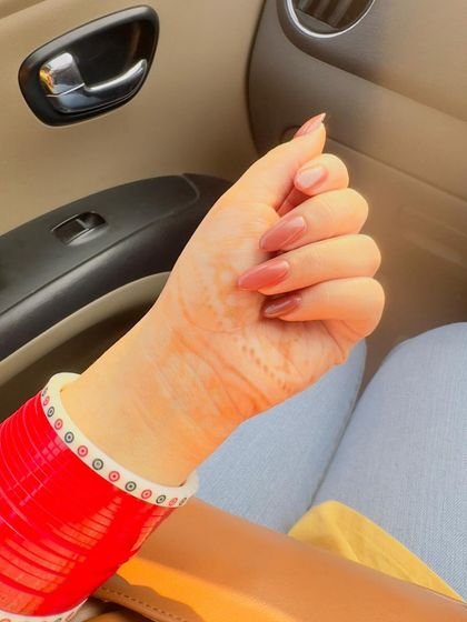 A simple, elegant nude manicure is perfect for any season. The red choora bangles make the nails pop.