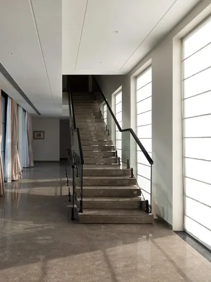 A long, sunlit corridor where the play of light and shadow becomes an architectural element in itself. The clean lines and polished marble floor create a serene and gallery-like passage through the home.