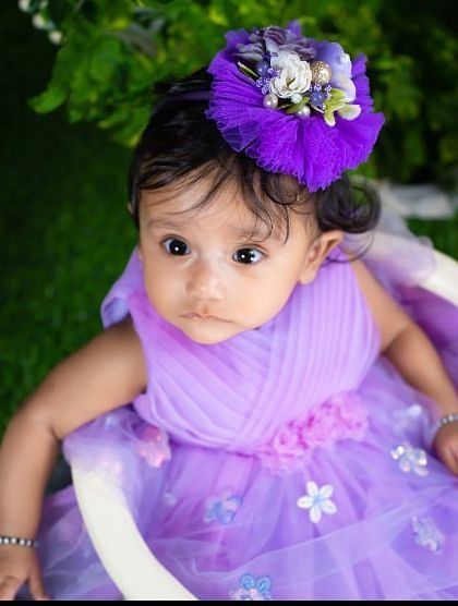 An overhead shot of a little girl in a purple dress, looking up with a curious expression.
