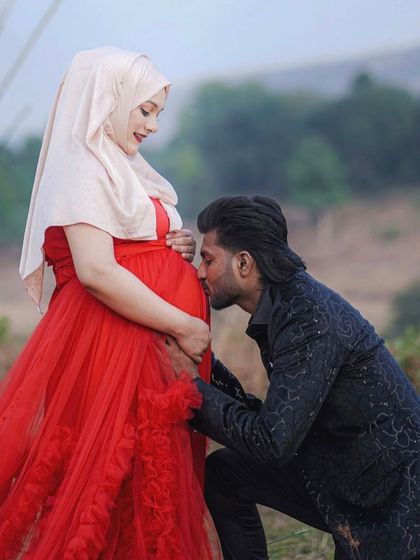 A tender kiss for the baby on the way. This outdoor couple's shoot is so full of love, enhanced by the dramatic red ruffled gown and the partner's coordinating dark blazer.