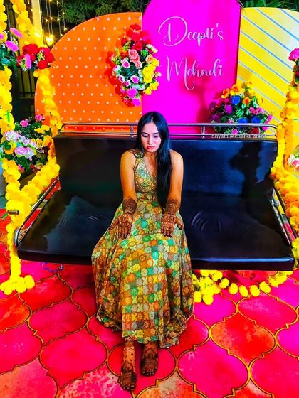 A bride seated at her colorful mehandi ceremony, her hands and feet beautifully adorned with my work.