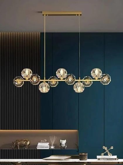 A linear chandelier with faceted crystal globes. This design combines a modern form with the classic sparkle of crystal, perfect for over a dining table.