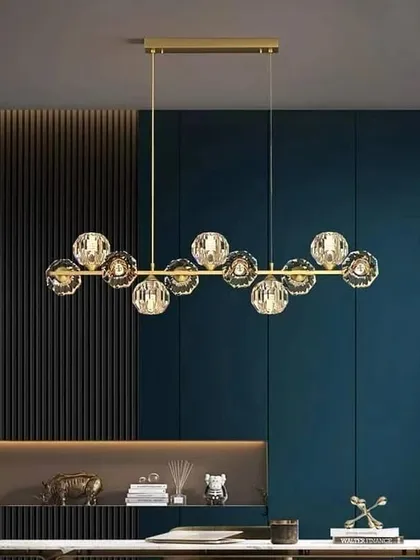 A linear chandelier with faceted crystal globes. This design combines a modern form with the classic sparkle of crystal, perfect for over a dining table.
