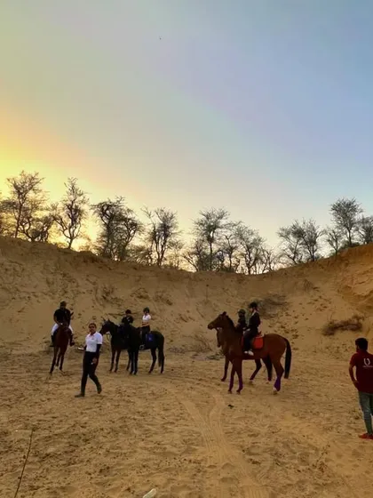 As the day ends, the light creates a magical atmosphere in the hills. Here, a group gathers on a sandy patch, with trainers nearby, showcasing a typical scene from our safari.