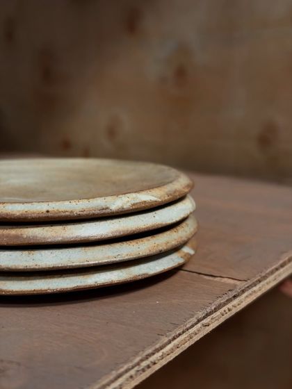A close-up stack of our handmade stoneware plates. You can see the texture and subtle variations that make each piece unique. They are high-fired for durability in your everyday life.