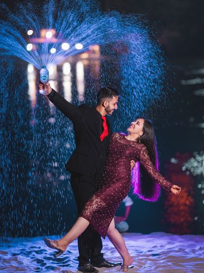 A fun and celebratory champagne spray shot, lit with dramatic blue light. This adds a party vibe to the pre-wedding shoot and results in a very dynamic photo.