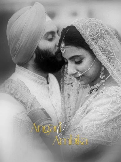 A soft, romantic black and white portrait of a Sikh couple, the groom gently kissing the bride's forehead.