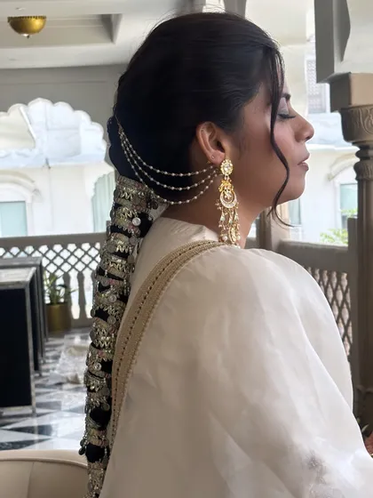 A profile shot that captures the elegance of the parandi braid. The soft tendrils framing the face add a touch of softness to this otherwise structured and dramatic hairstyle.