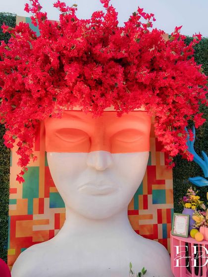 Art and nature collide in this striking installation featuring a stoic head sculpture crowned with a vibrant explosion of red bougainvillea. This piece exemplifies my approach of using unexpected combinations to create memorable focal points.