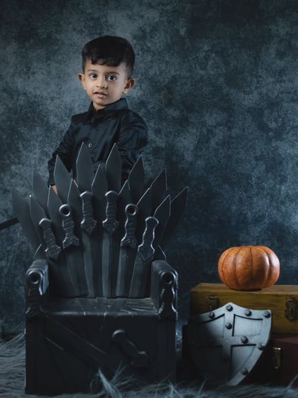 This toddler is contemplating his next move as the ruler of the kingdom, sitting thoughtfully on the Iron Throne.
