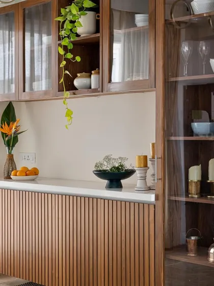 A close-up of a floating crockery unit with fluted wood base cabinets and glass-fronted display shelves.
