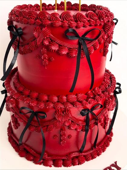 A close-up of the intricate, hand-piped detailing on our bold red "Scorpio Baby" cake. The vintage-style piping and black ribbon accents create a dramatic and luxurious texture.