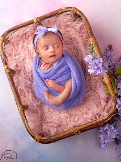 Another angle of this sweet newborn, swaddled in purple and sleeping soundly. These are the peaceful moments we aim to capture.