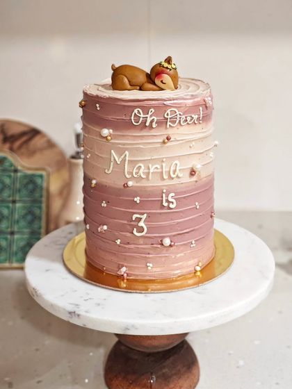 Oh Deer. This tall cake was for Maria's third birthday. It features a rustic, textured buttercream finish in ombre shades and a cute little sleeping deer on top.